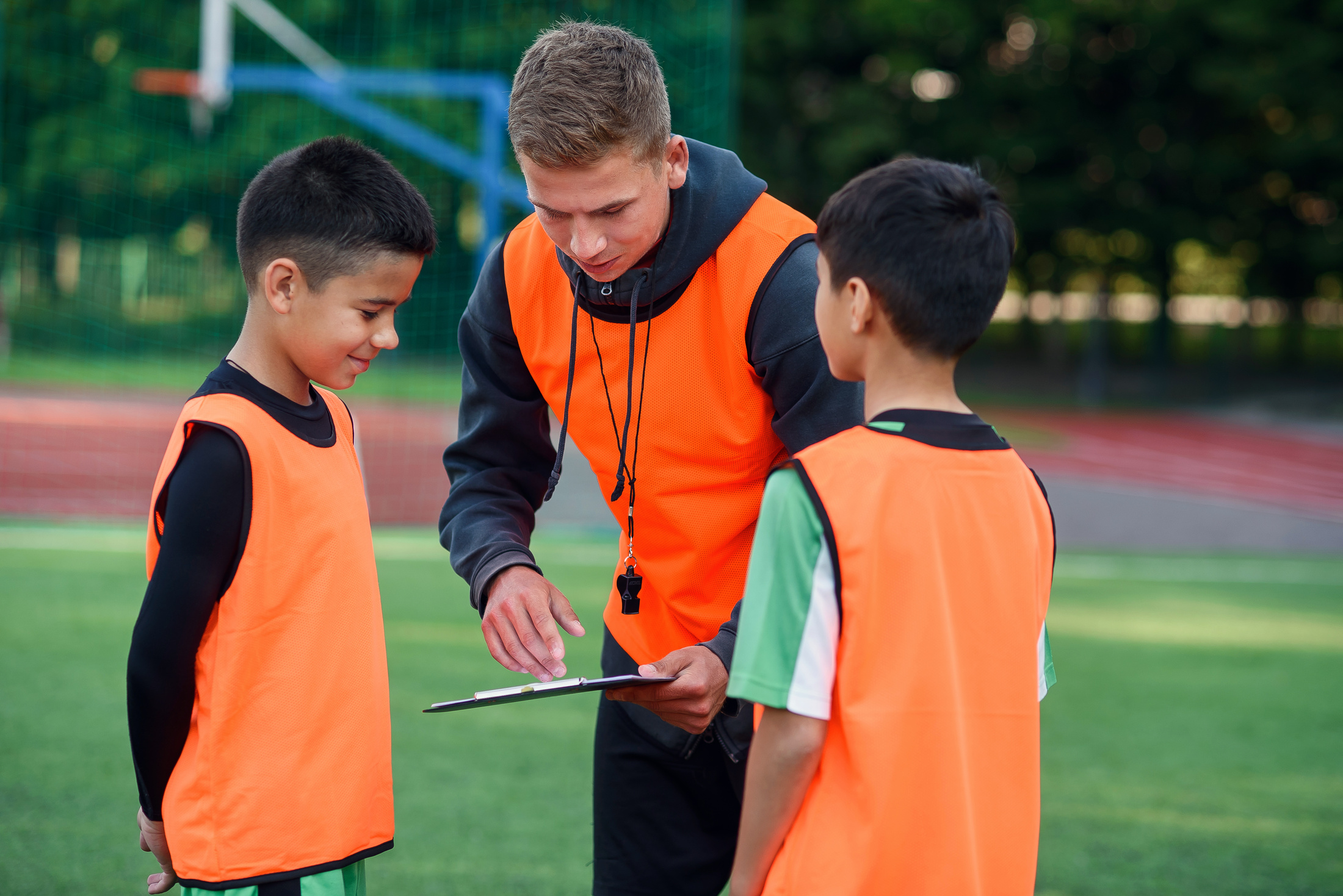 Football Coach Instruct Teen Football Players. Young Professional Coach Explains for Kids the Strategy of the Game.